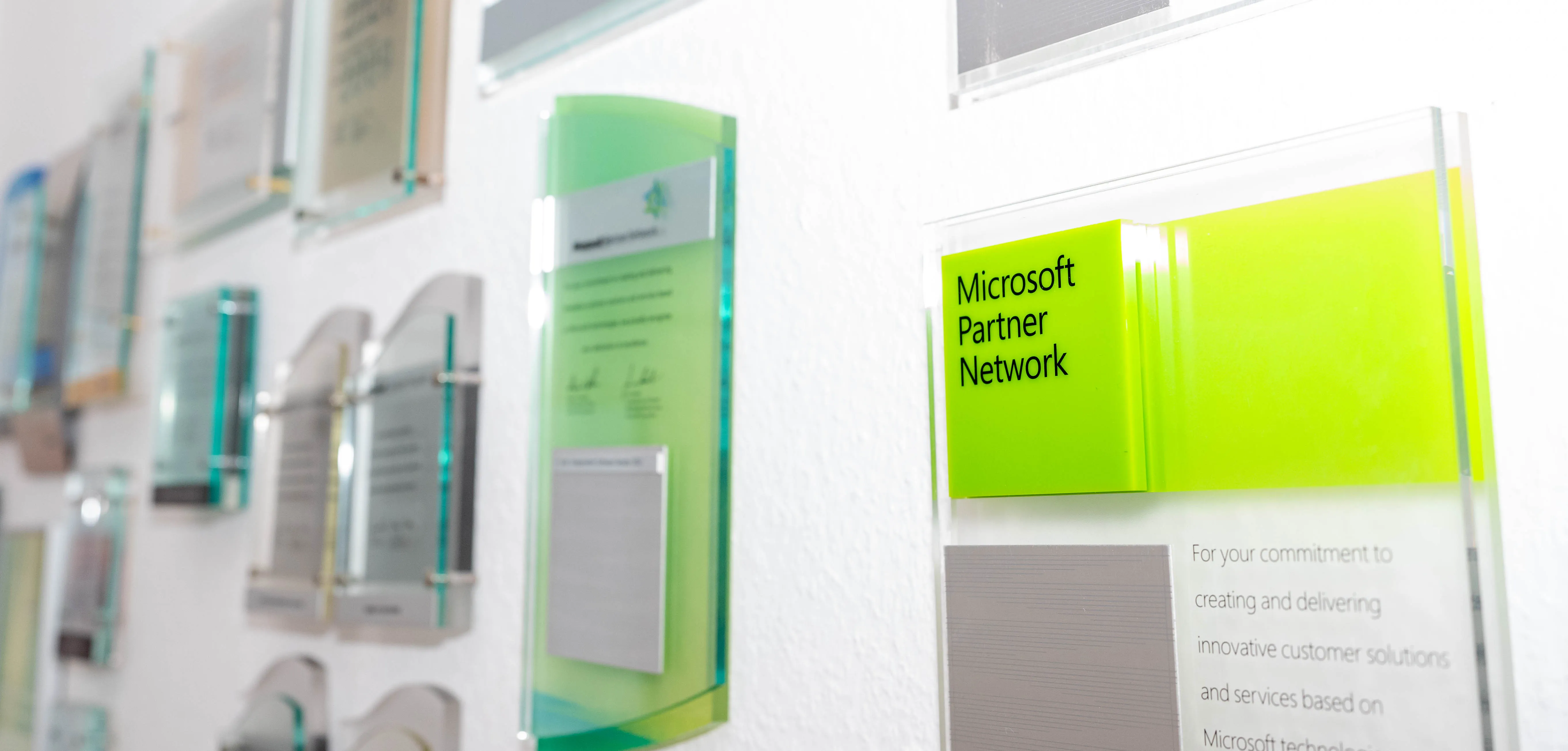 Auszeichnungs- und Partnerwand mit Glas-Awards und dem Microsoft-Partner-Network-Schild